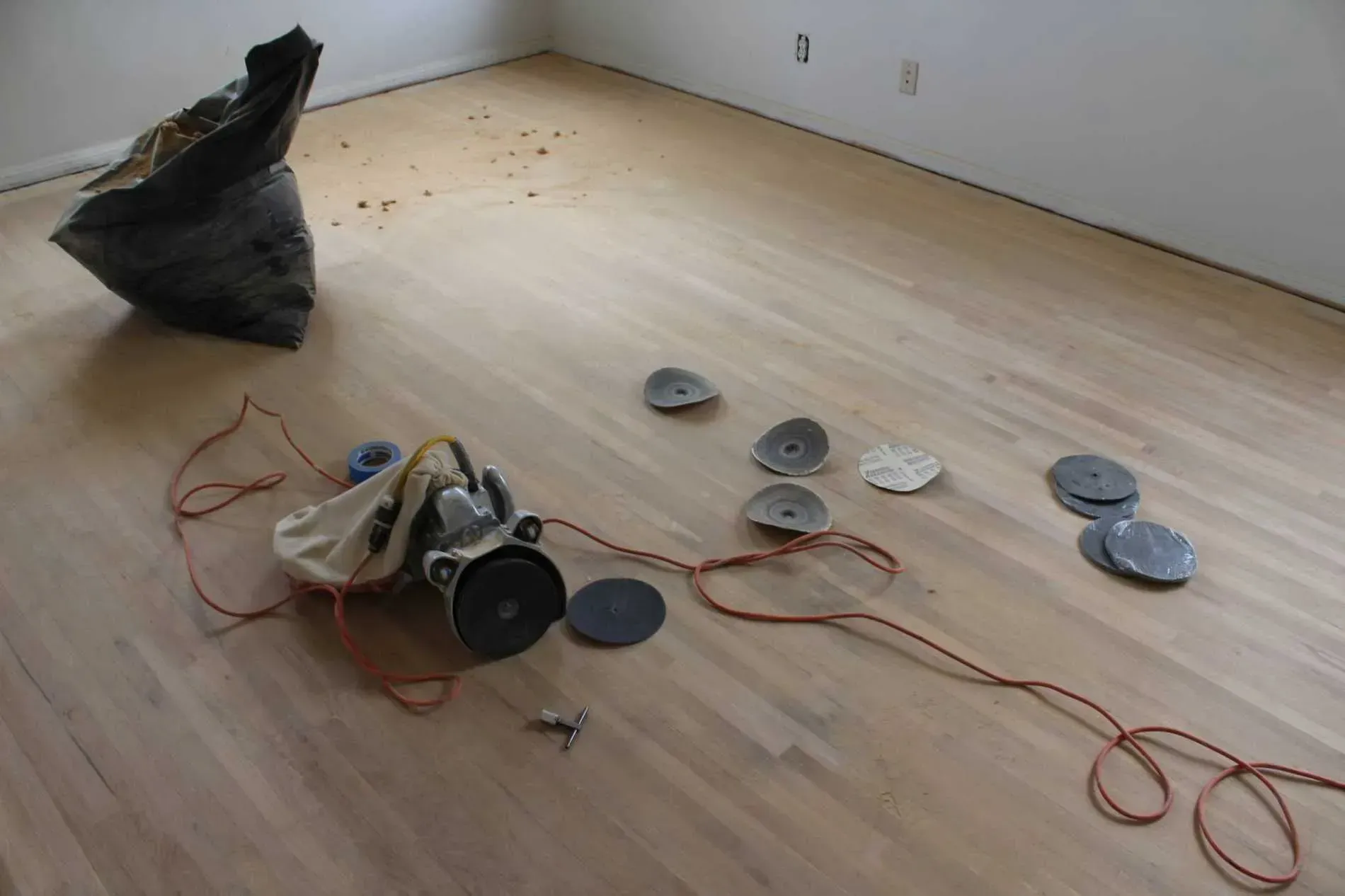 A vacuum cleaner is sitting on a wooden floor next to a bag