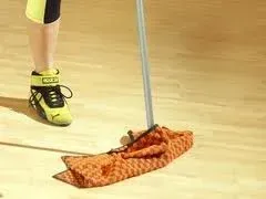 A person is mopping a wooden floor with a mop.