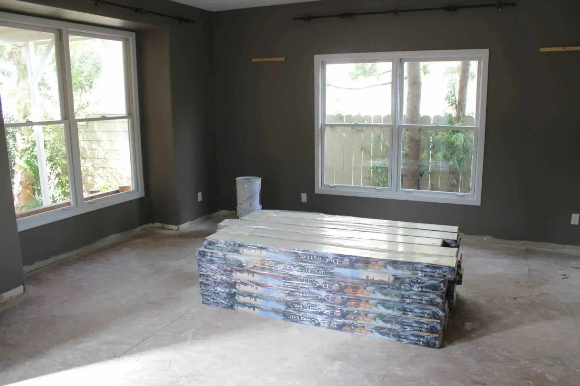 An empty living room with a wooden table and two windows.