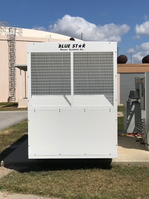 White Blue Star utility unit with vented front panels and solar panels, outdoors on grass near a building