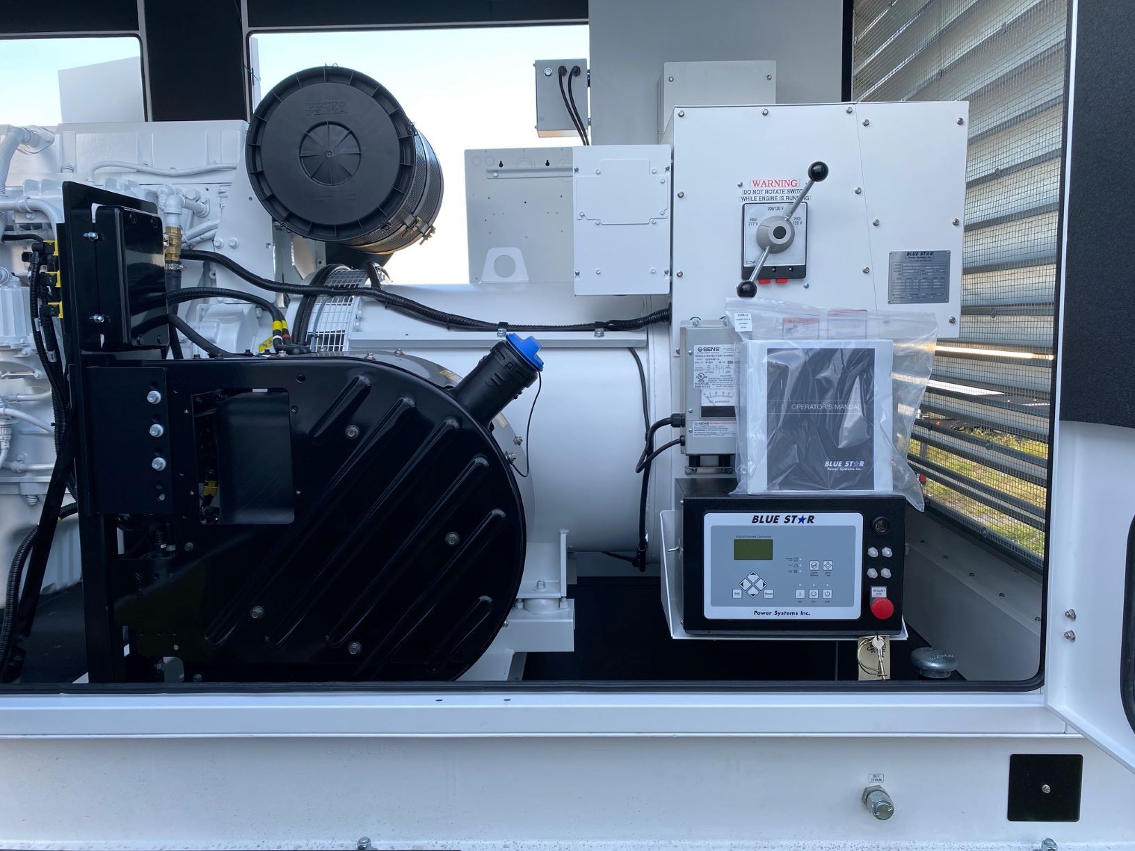 Industrial machine with gauges and wiring mounted on a white metal panel in a workshop.