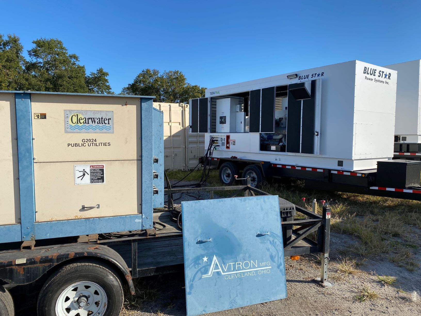 Mobile white trailer and equipment on a lot under a clear blue sky