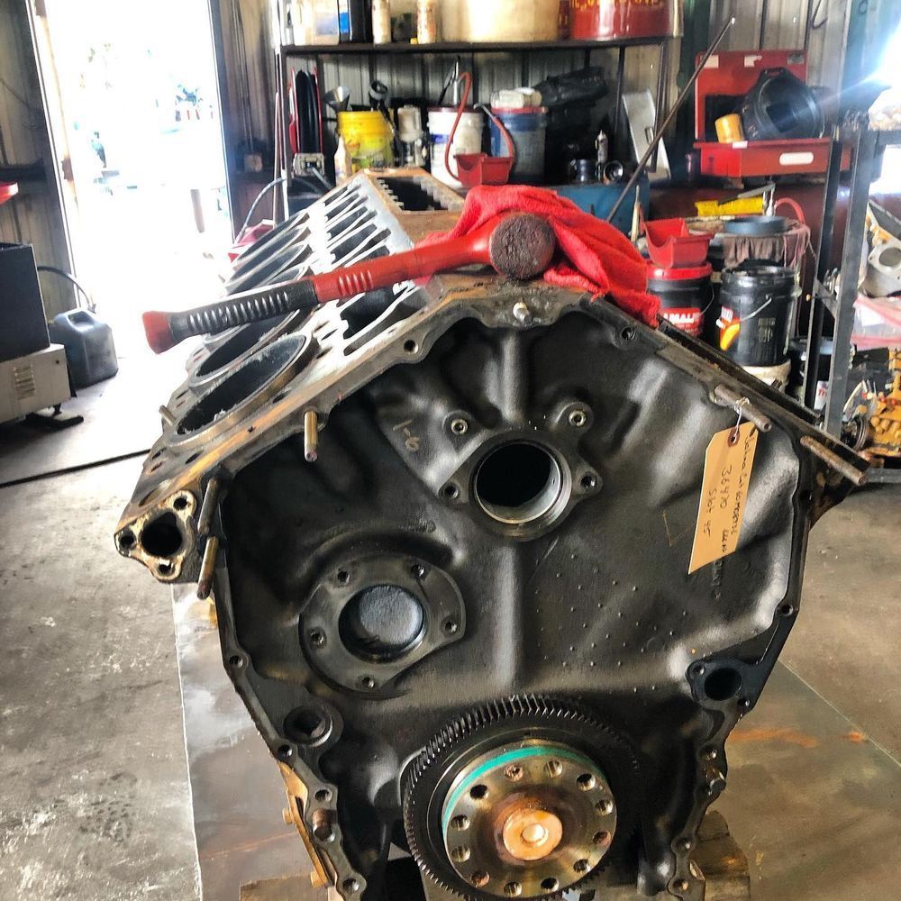 Engine block in a workshop, with a red strap draped over the top and shelves in the background.