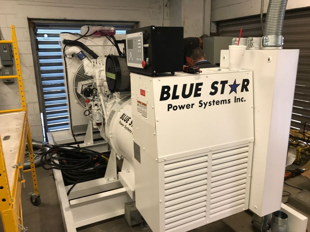 Blue Star industrial generator in a warehouse, with white casing and exposed wiring