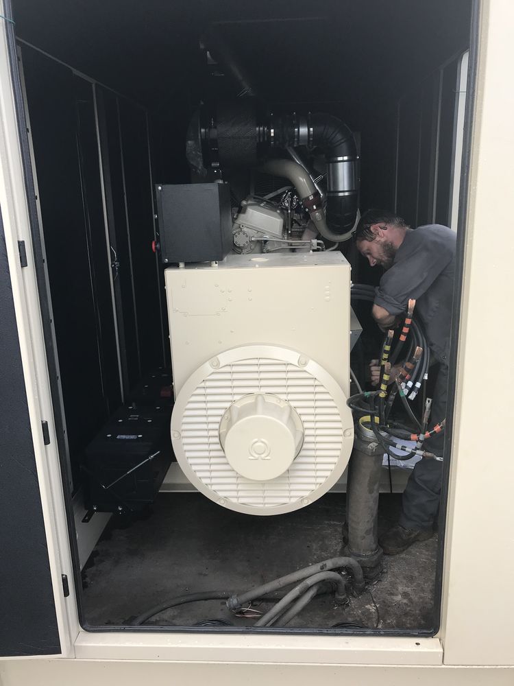 Technician working on a large industrial generator inside a dark equipment enclosure