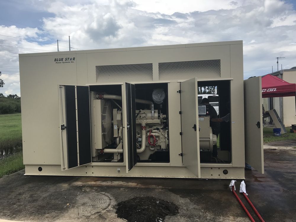 Open electrical generator cabinet with doors open, showing machinery inside outdoors on a cloudy day