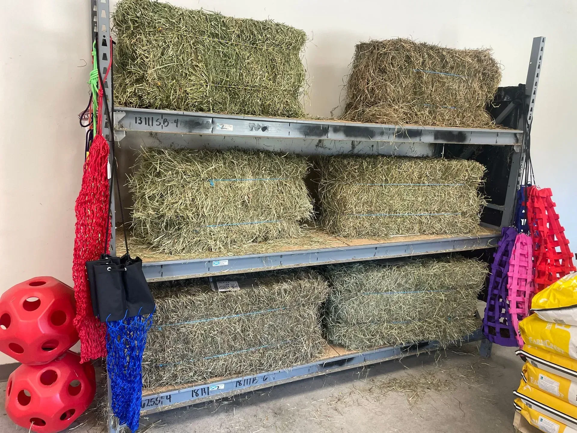 Hay bales stacked on metal shelves in a storage area.