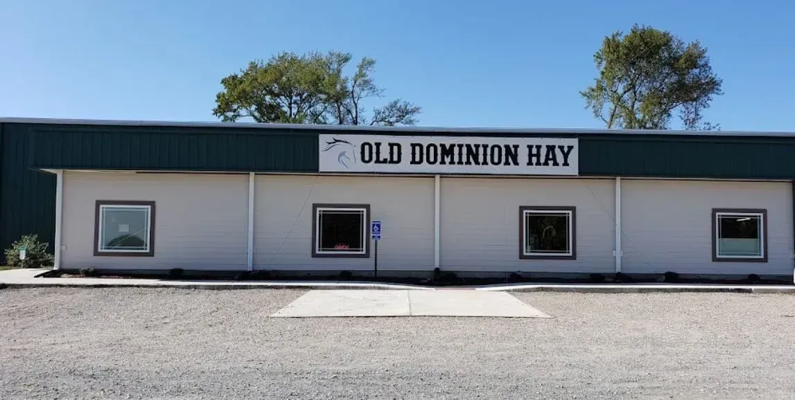 Old Dominion Hay building with a blue roof, white walls, and three windows.