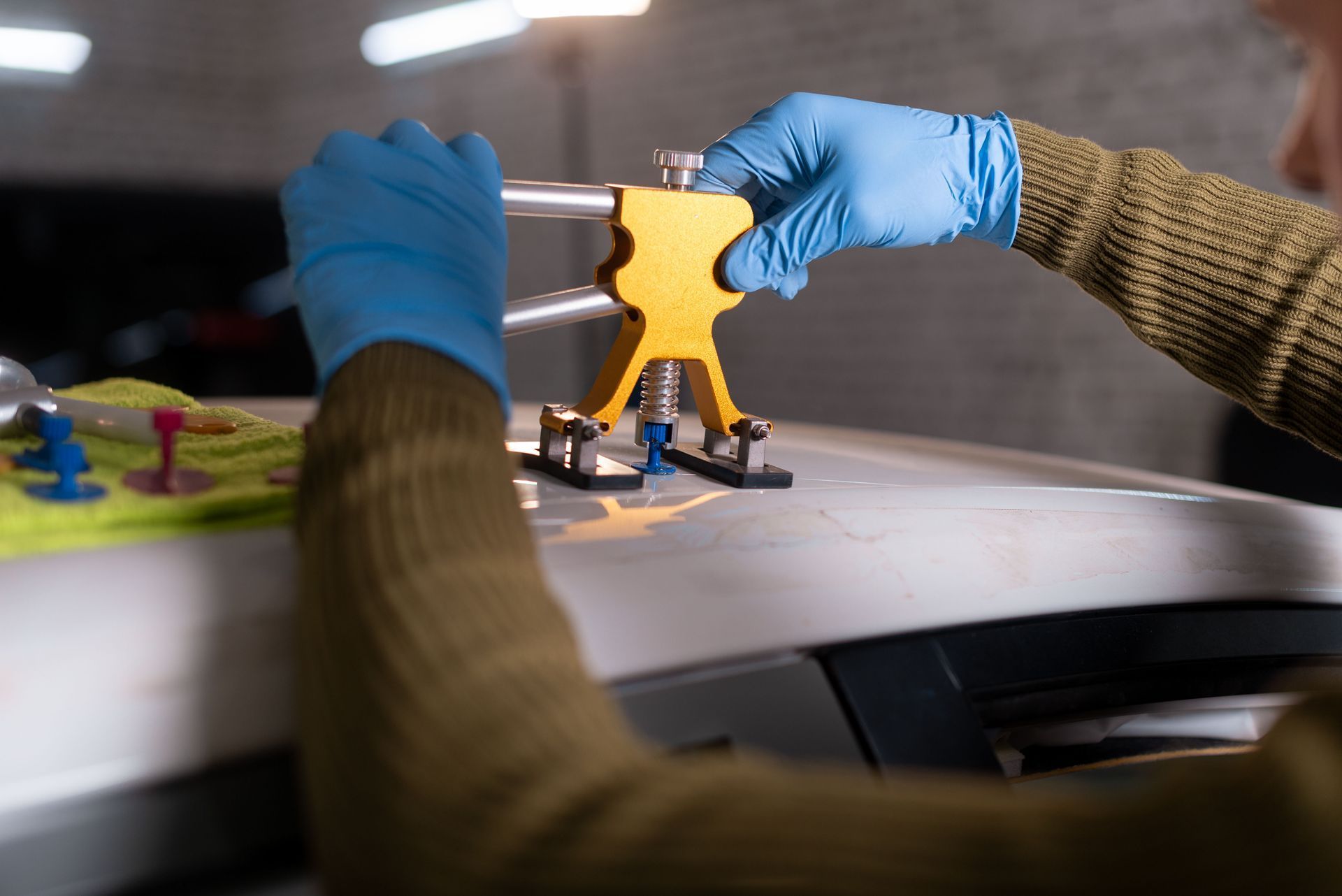 Gloved hands operating a yellow 3D printer or mechanical tool on a workbench