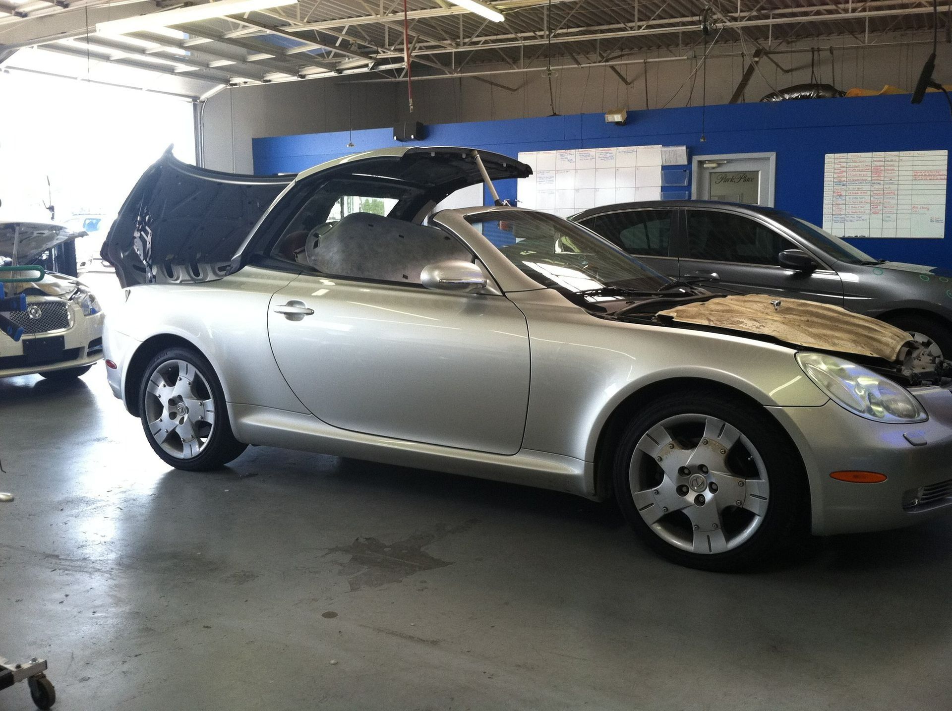 Silver convertible car in an auto shop, with the hood and trunk open.