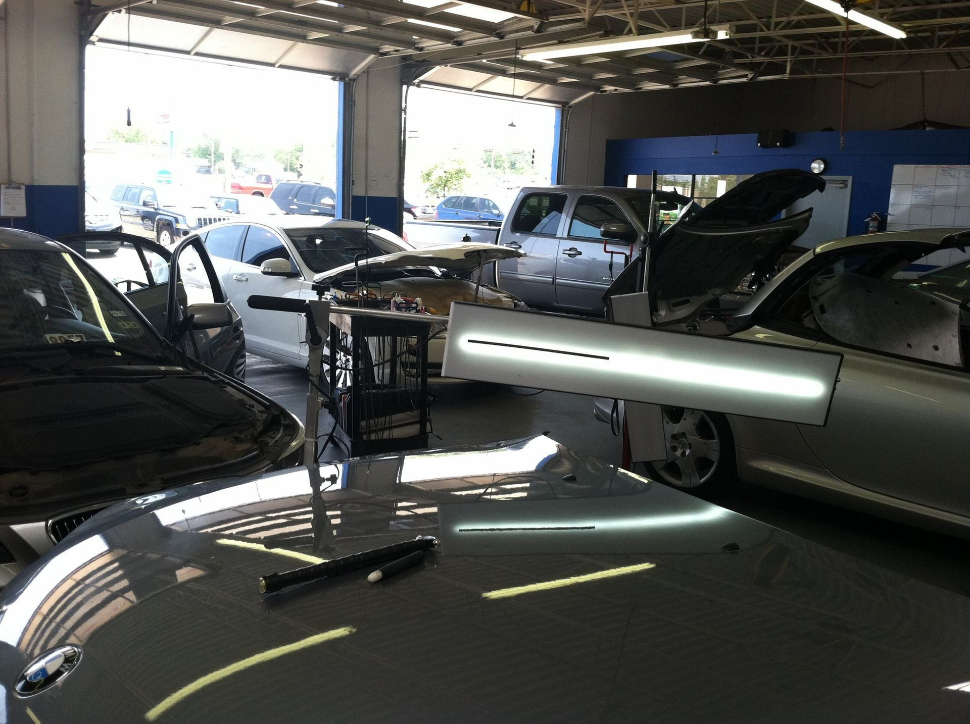 Cars inside an auto repair shop with hoods open under bright garage lights