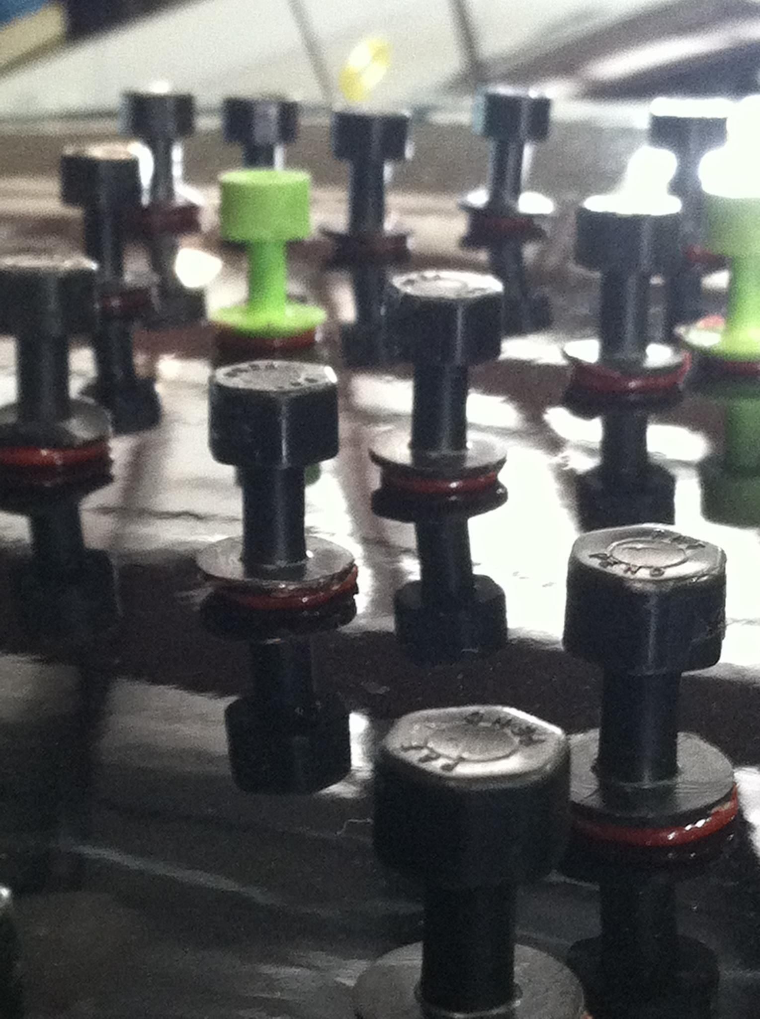 Close-up of black and red push pins on a corkboard, with one green push pin in the center
