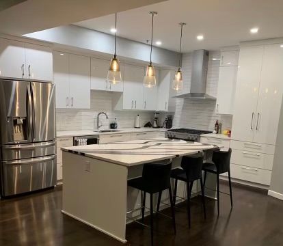 A kitchen with white cabinets , stainless steel appliances , and a large island.