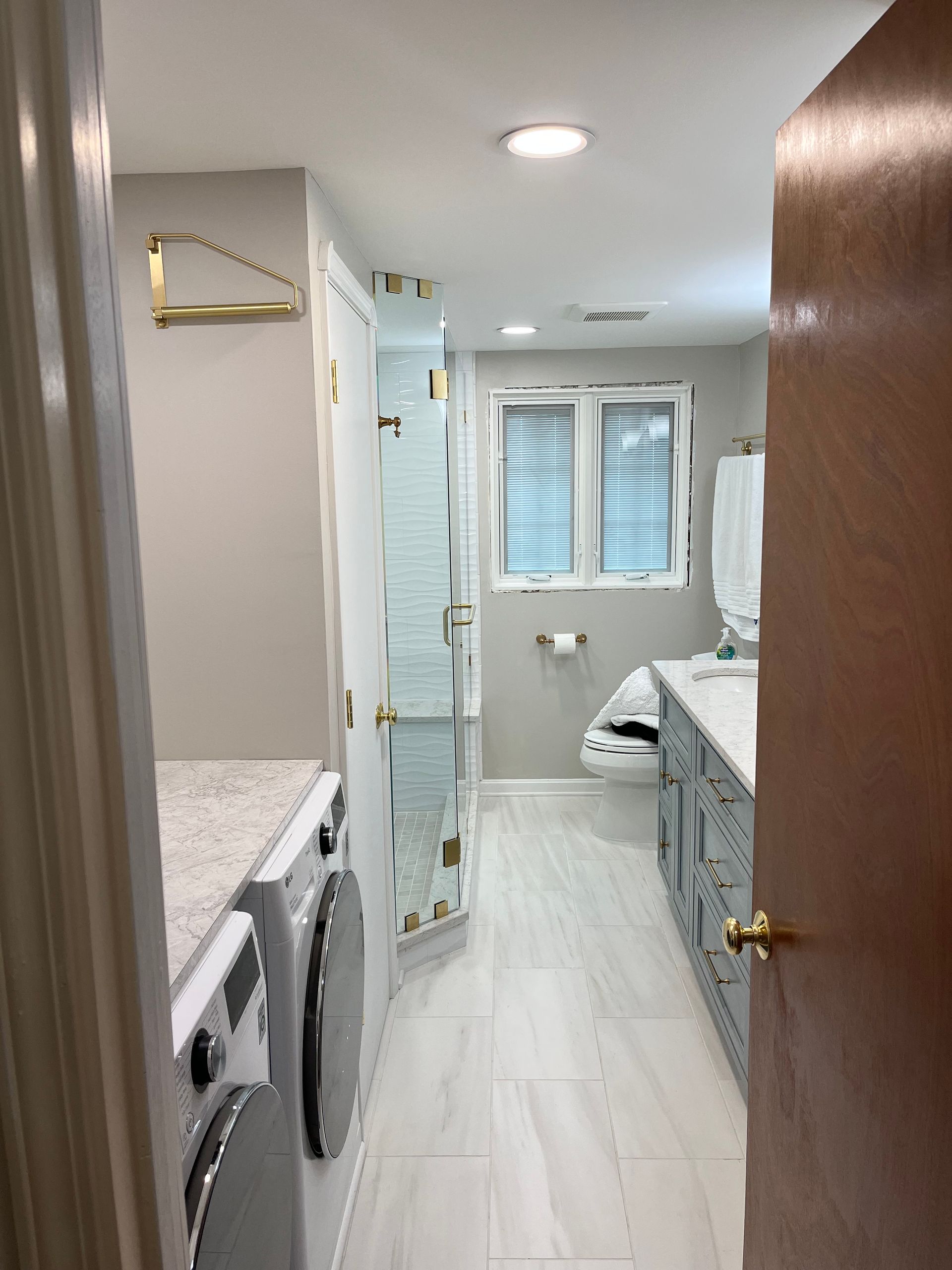 A laundry room with a washer and dryer and a bathroom with a walk in shower.