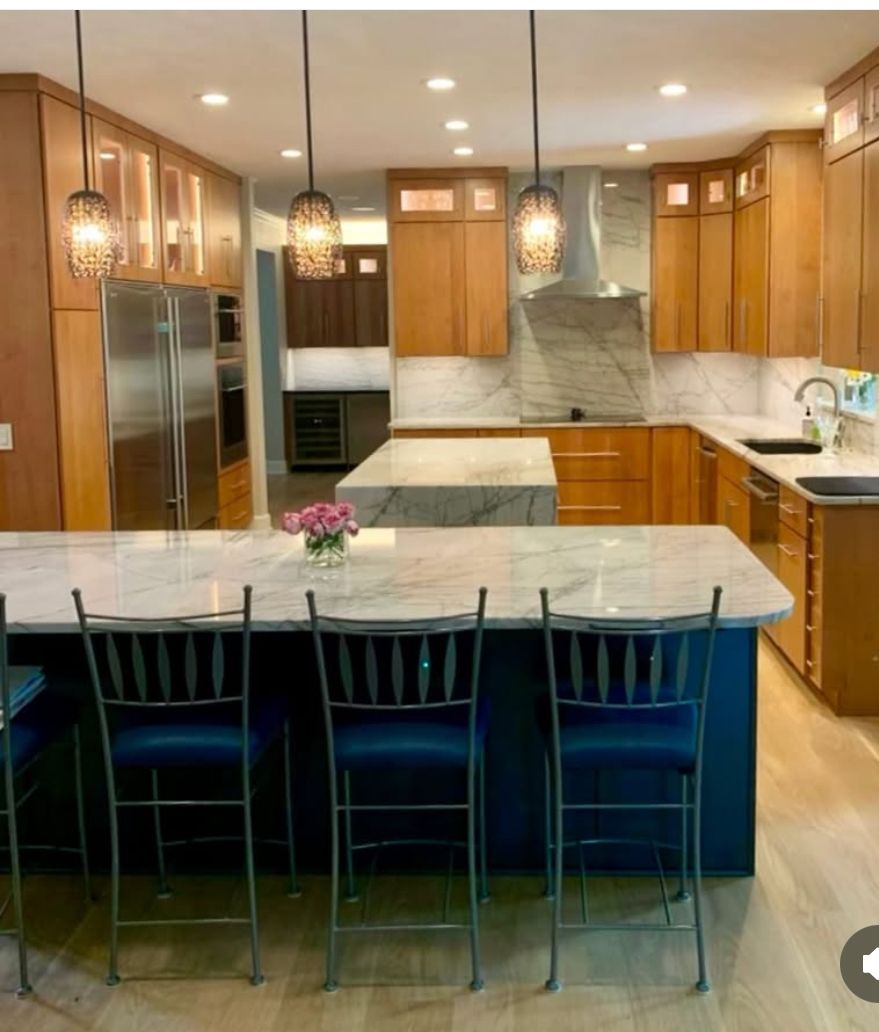 A kitchen with a marble counter top and chairs