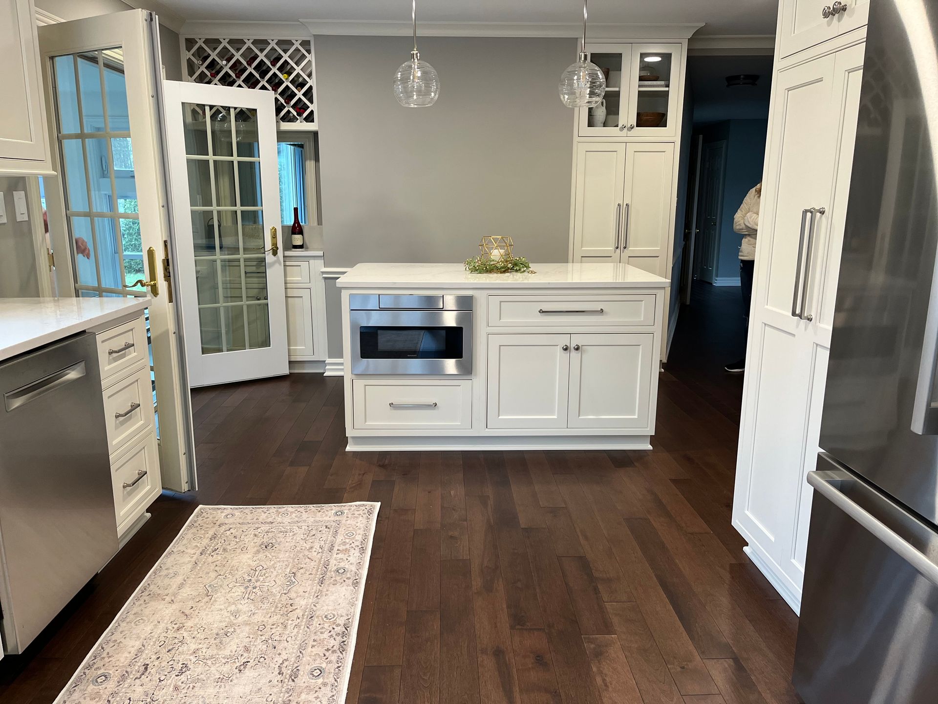 A kitchen with white cabinets , stainless steel appliances , hardwood floors and a large island.