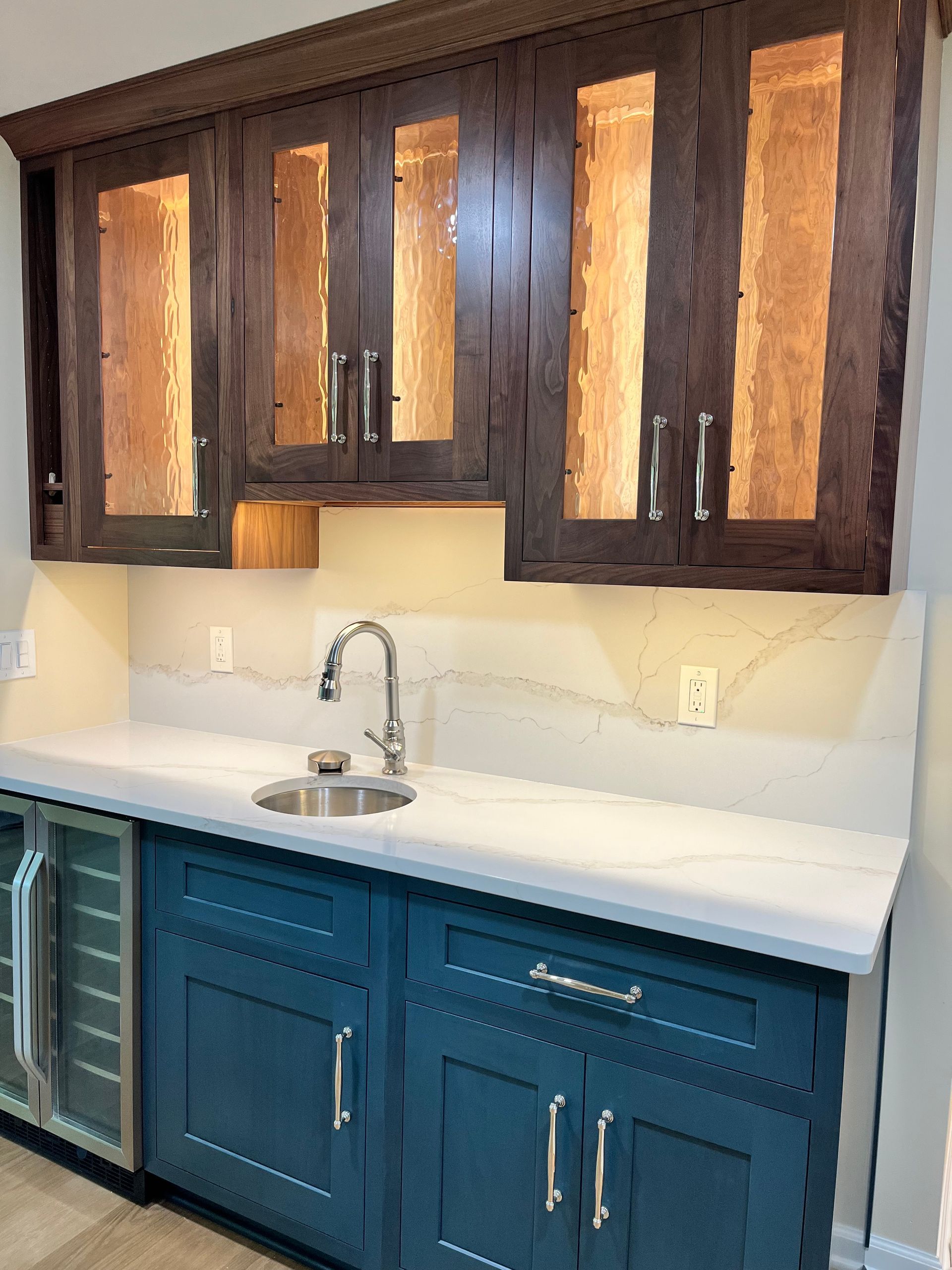 A kitchen with blue cabinets , a sink , and a refrigerator.