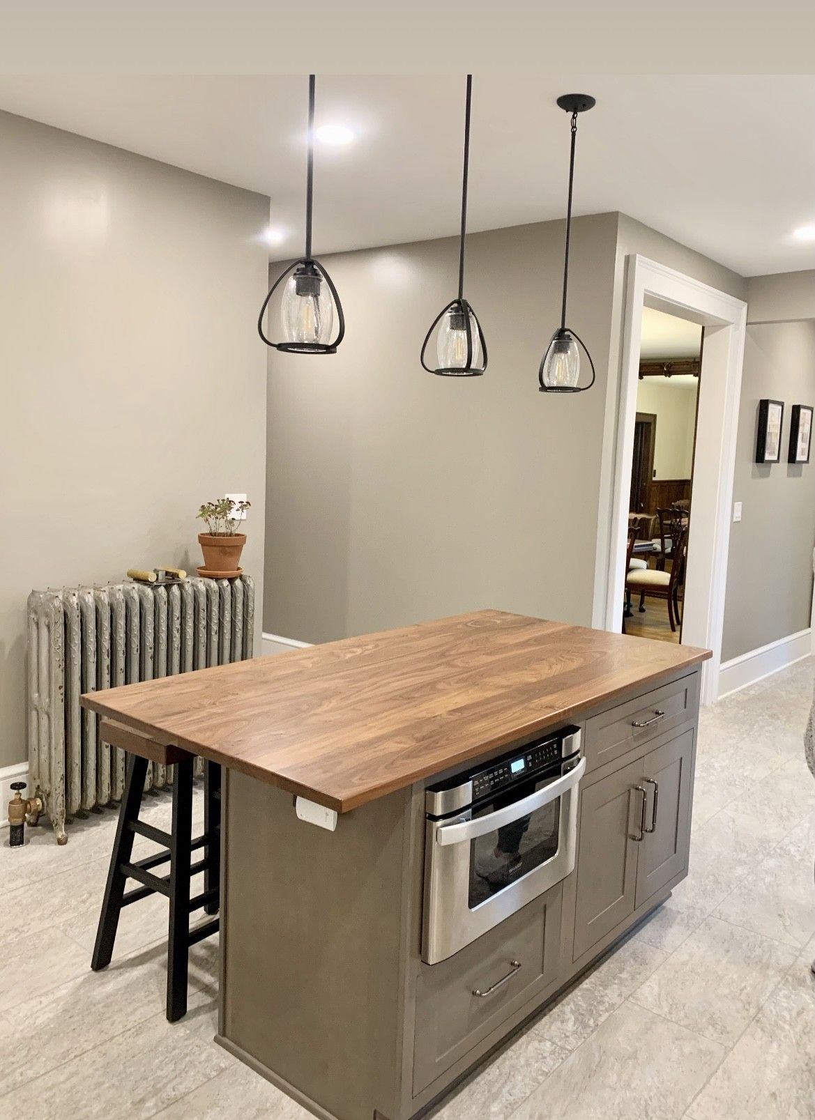 A kitchen with a large island with a wooden top and stools.