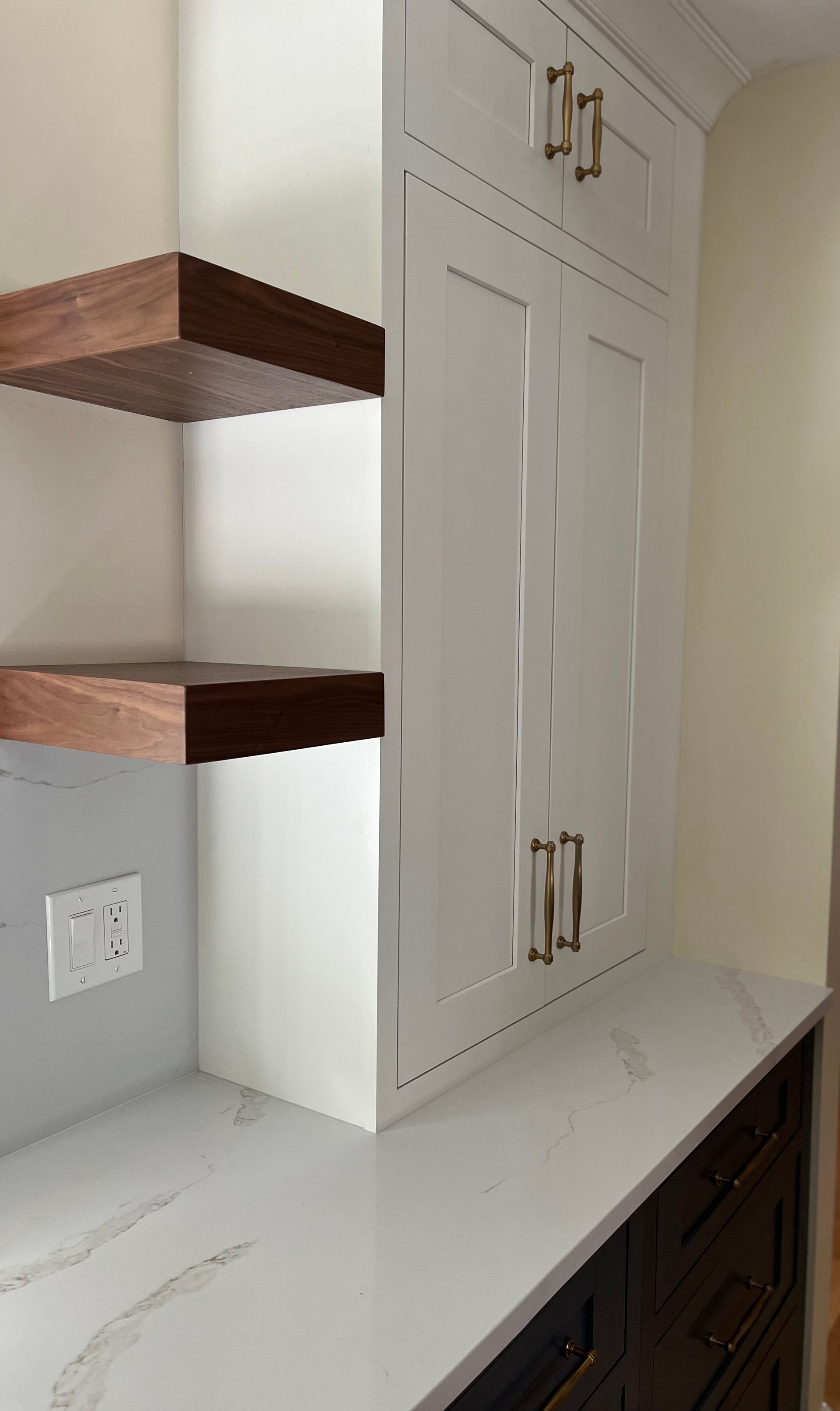 A kitchen with white cabinets and wooden shelves.