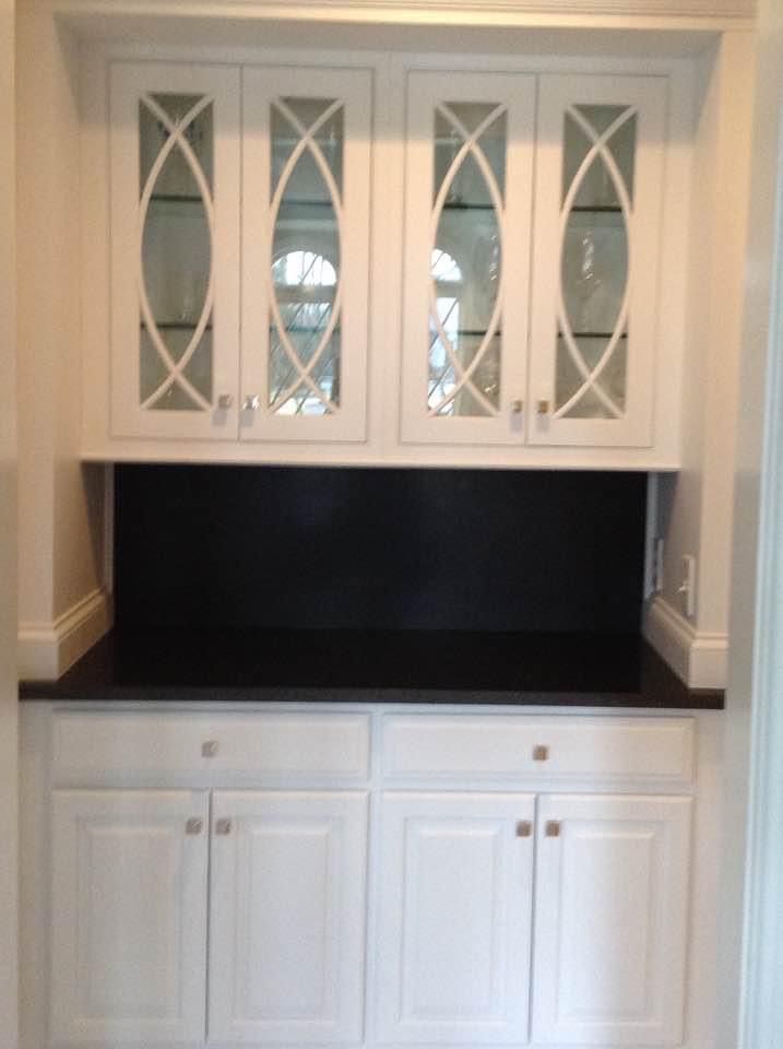 A kitchen with white cabinets and black counter tops.