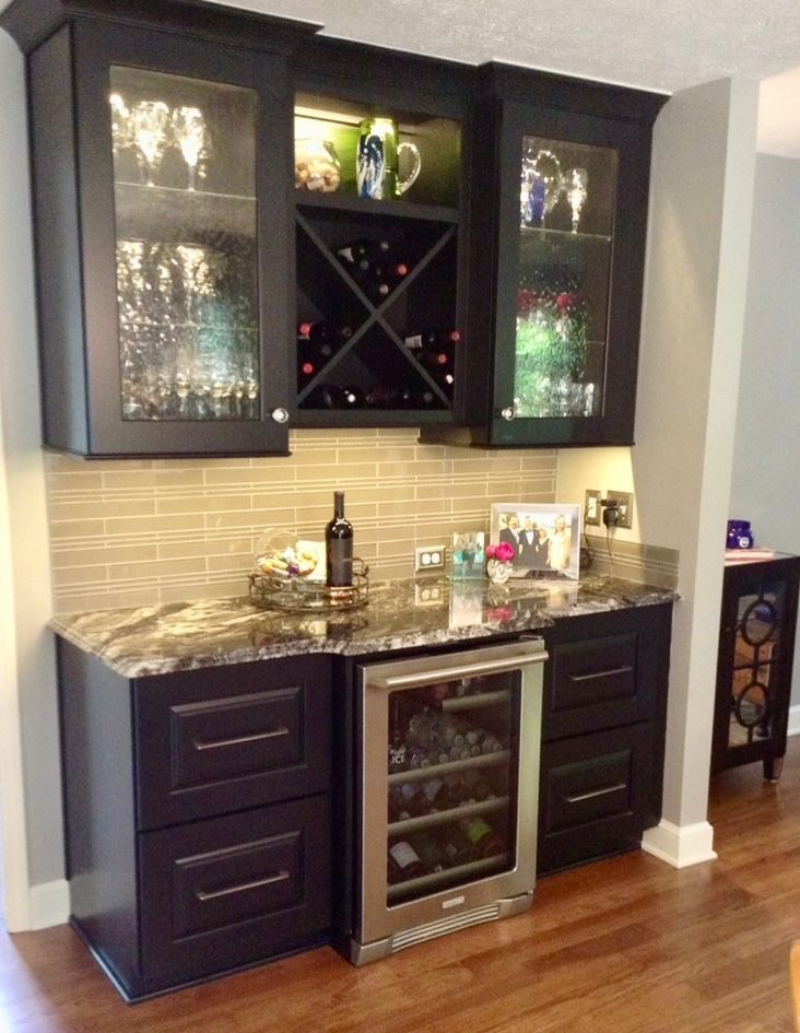 A kitchen with black cabinets and a wine cooler