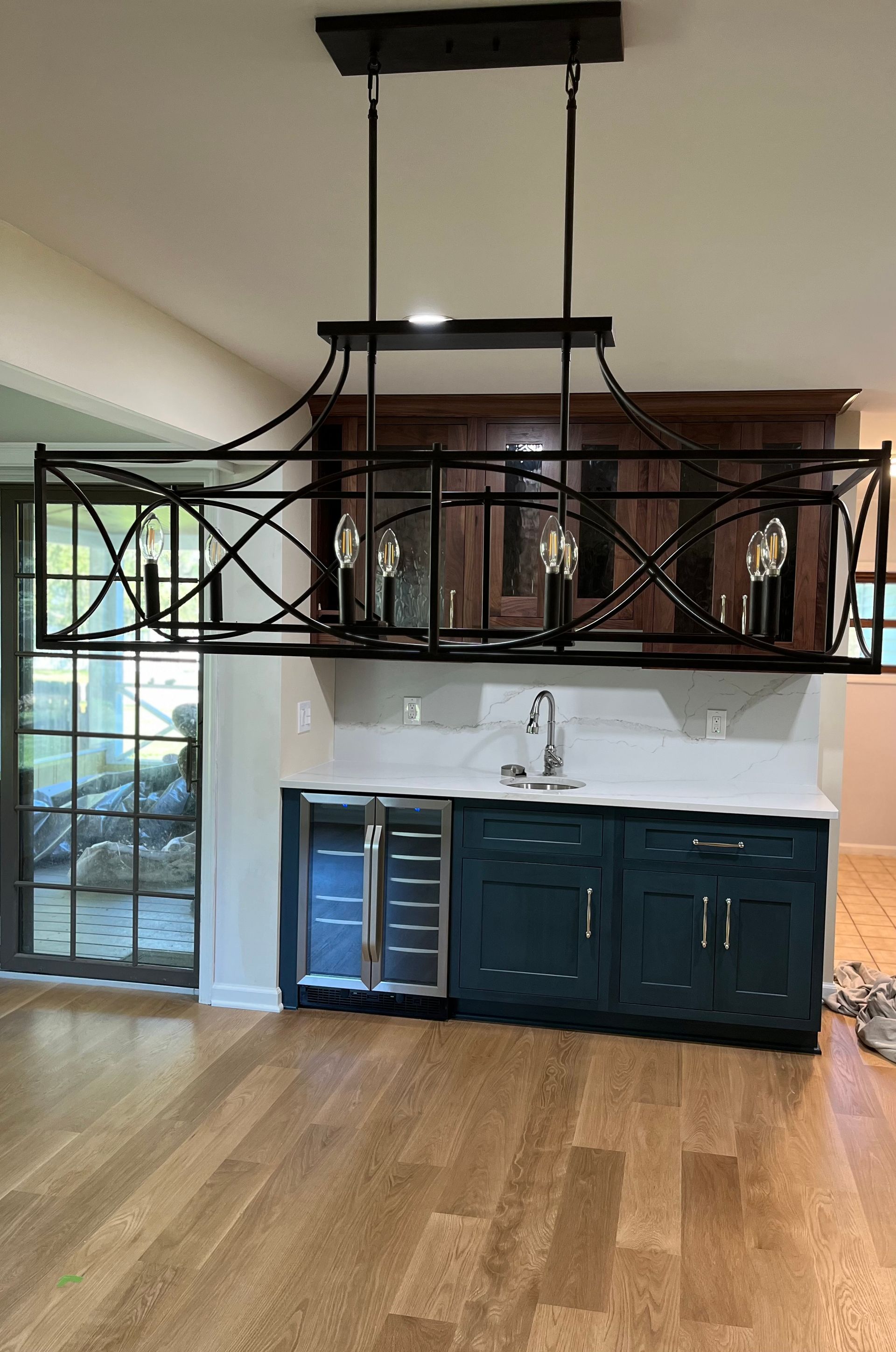A kitchen with a sink , refrigerator , and chandelier.