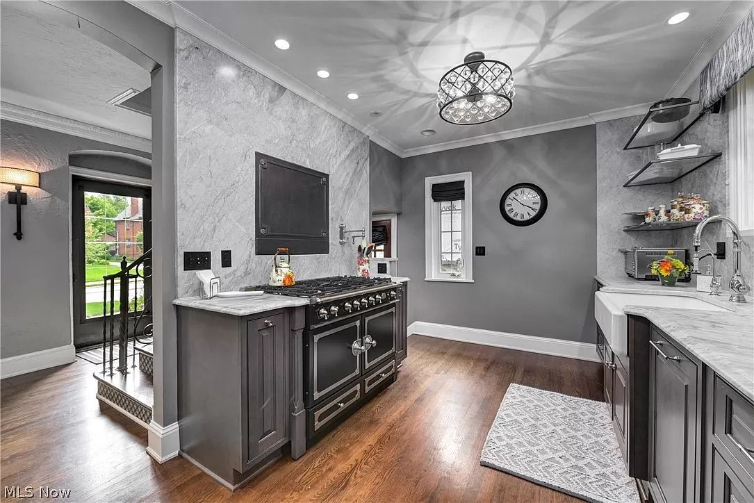 A kitchen with a stove and a television on the wall.