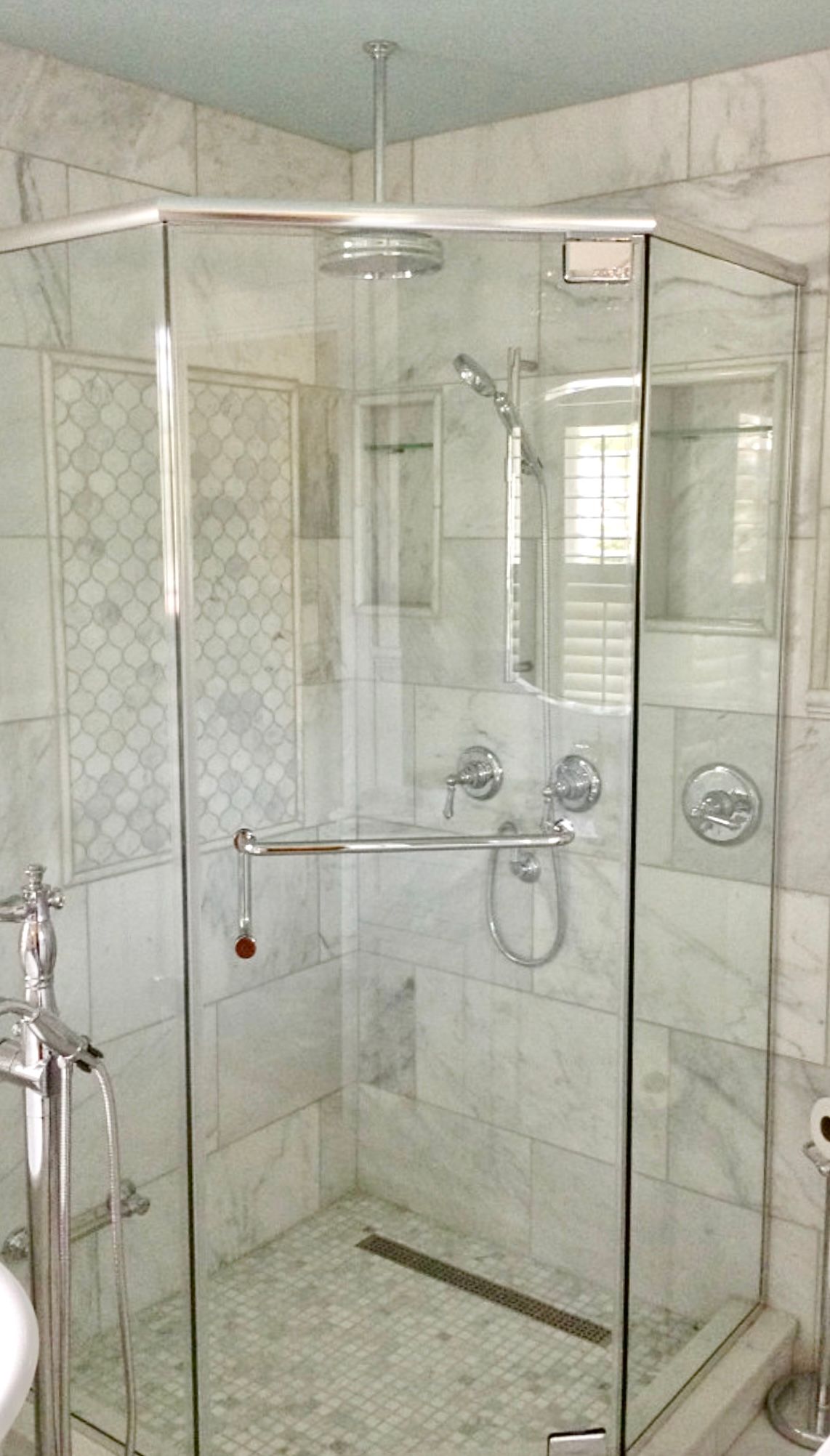 A bathroom with a walk in shower with a glass door.