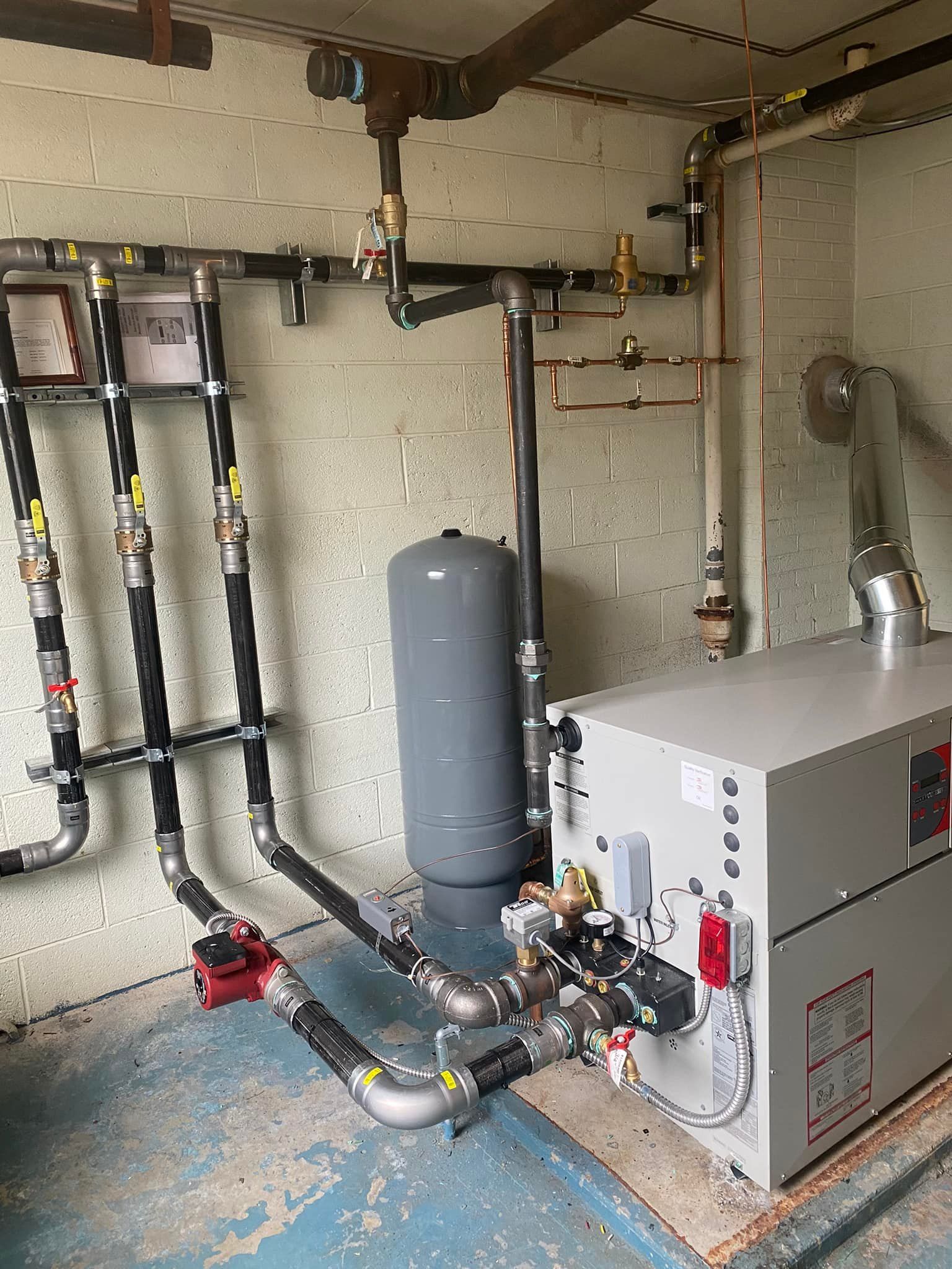 A room with a boiler and a lot of pipes.