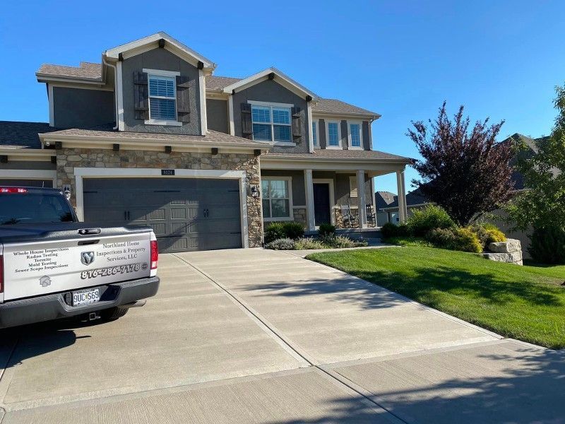 Suburban two-story house with a driveway, garage, and a pickup truck parked in front.