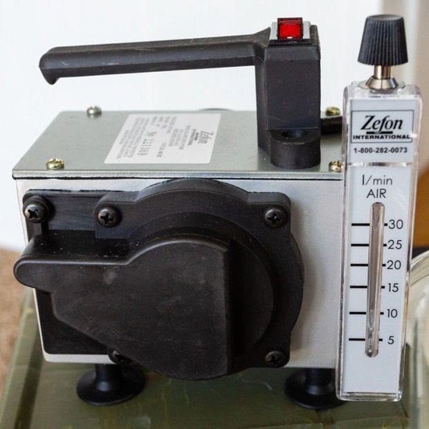 Small black air pump or compressor with gauge and clear flow meter on the right