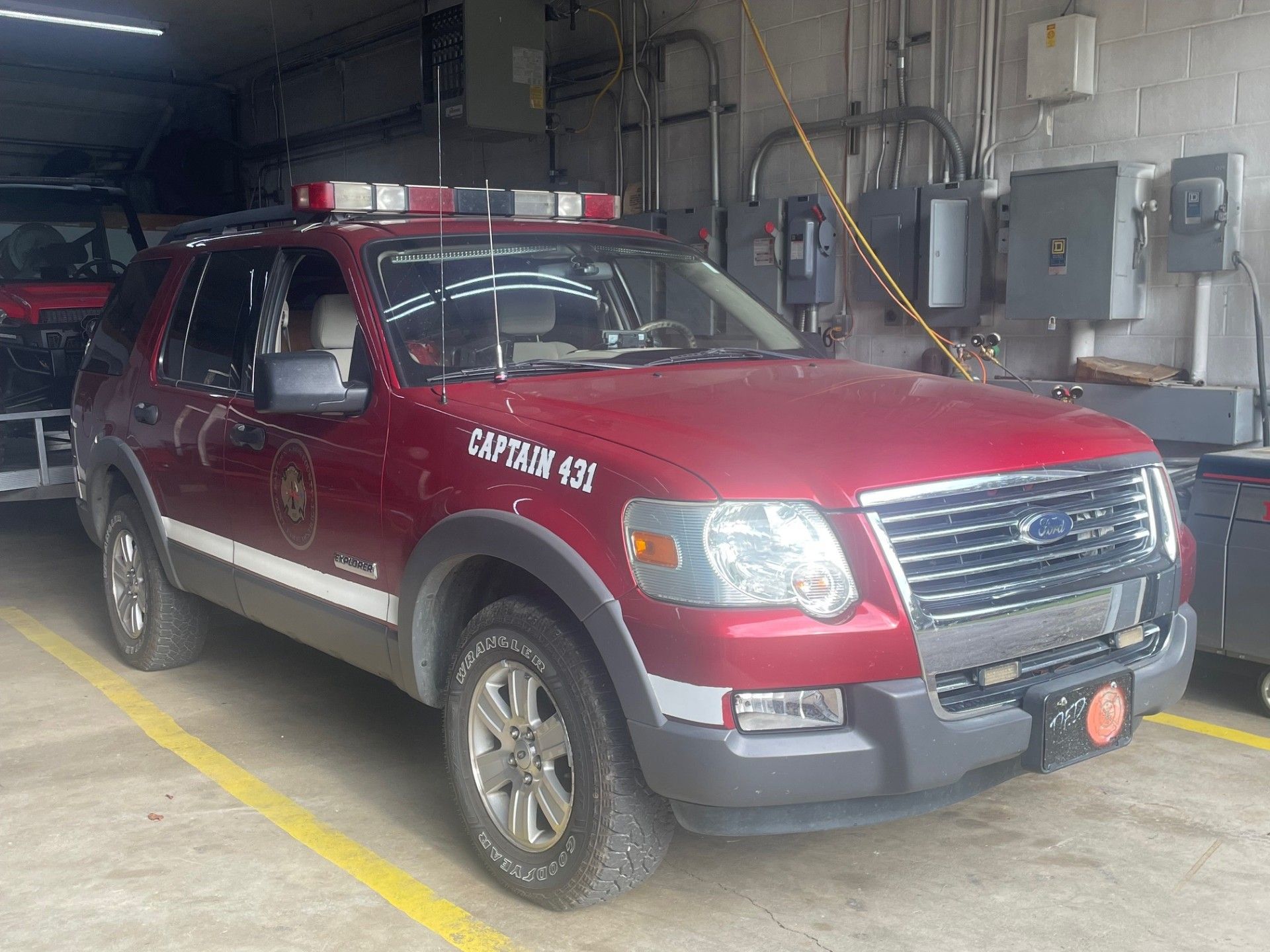 Red Ford Explorer fire chief vehicle inside a station, with emergency lights on top.