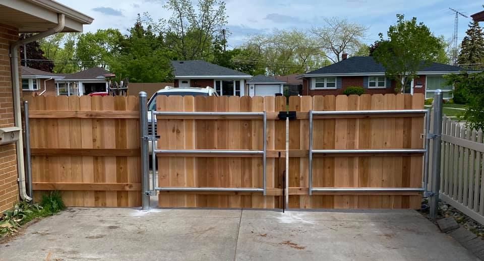 Wooden backyard gate with metal frame and concrete driveway, viewed from outside a house.