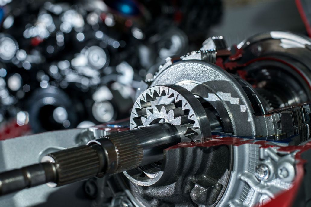 Close-up of a metallic gear and shaft assembly inside a machine, with red and silver components.