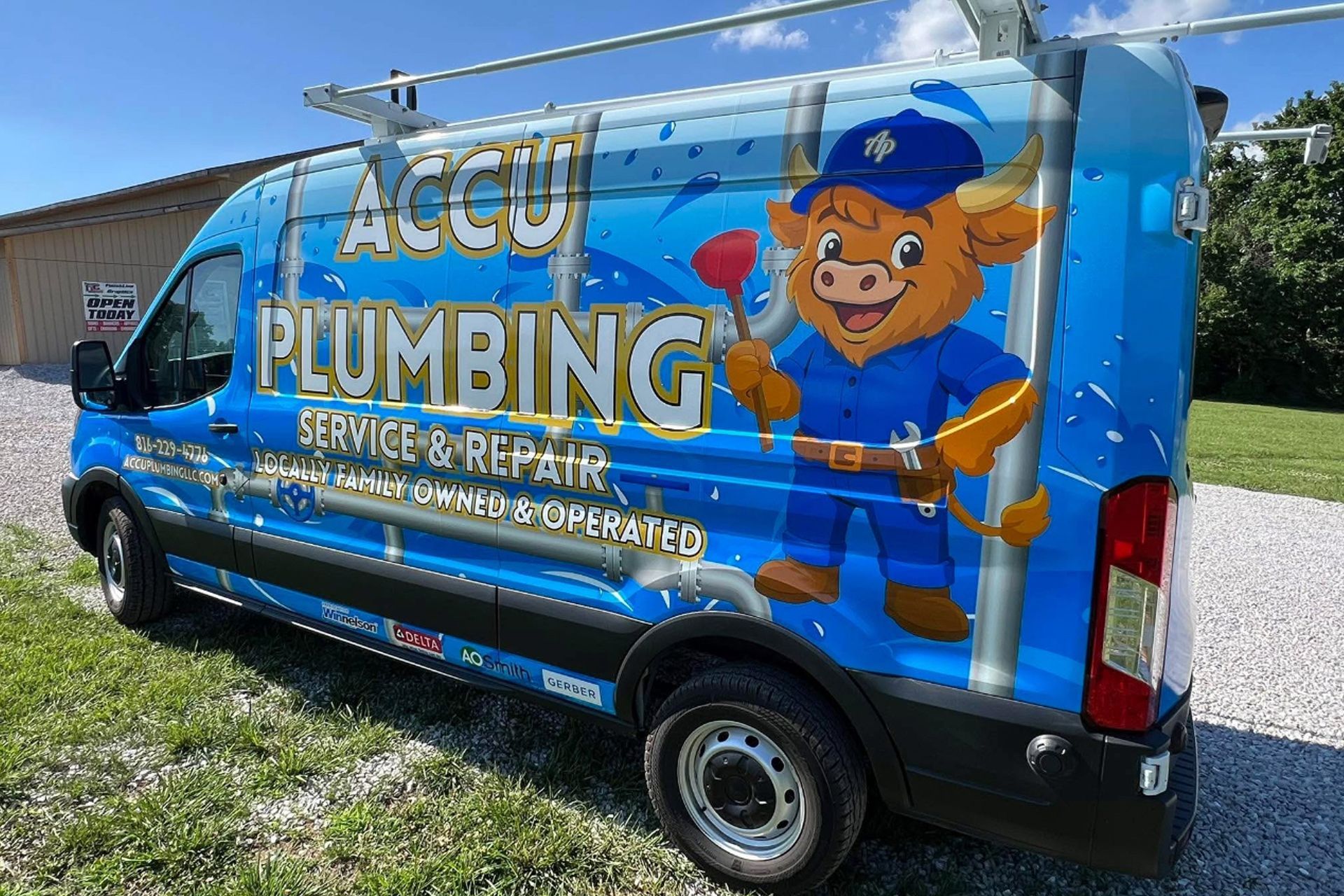 Accu Plumbing van with bull mascot holding a plunger; blue and white graphics; parked outdoors.
