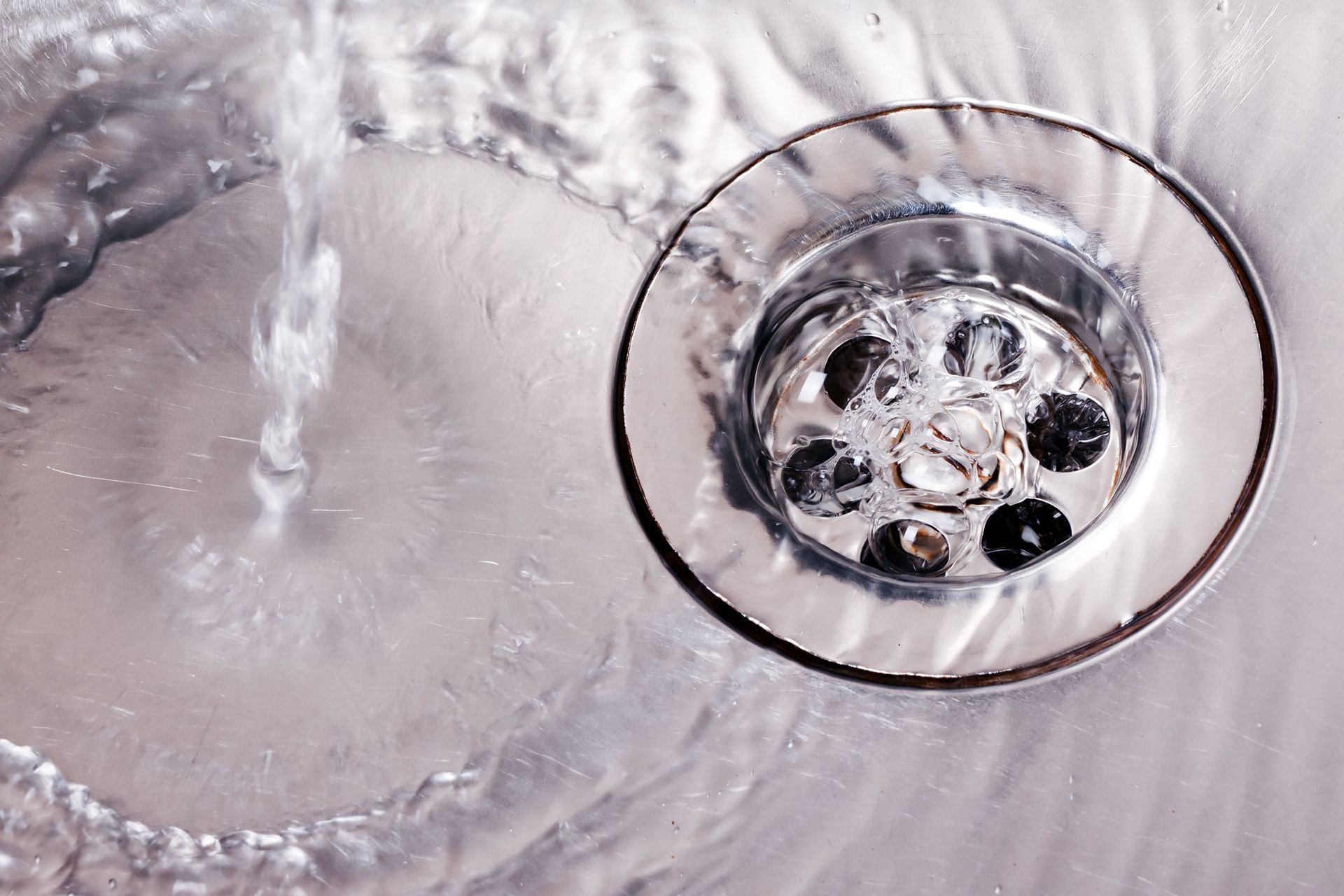 Water flowing into a silver sink drain.