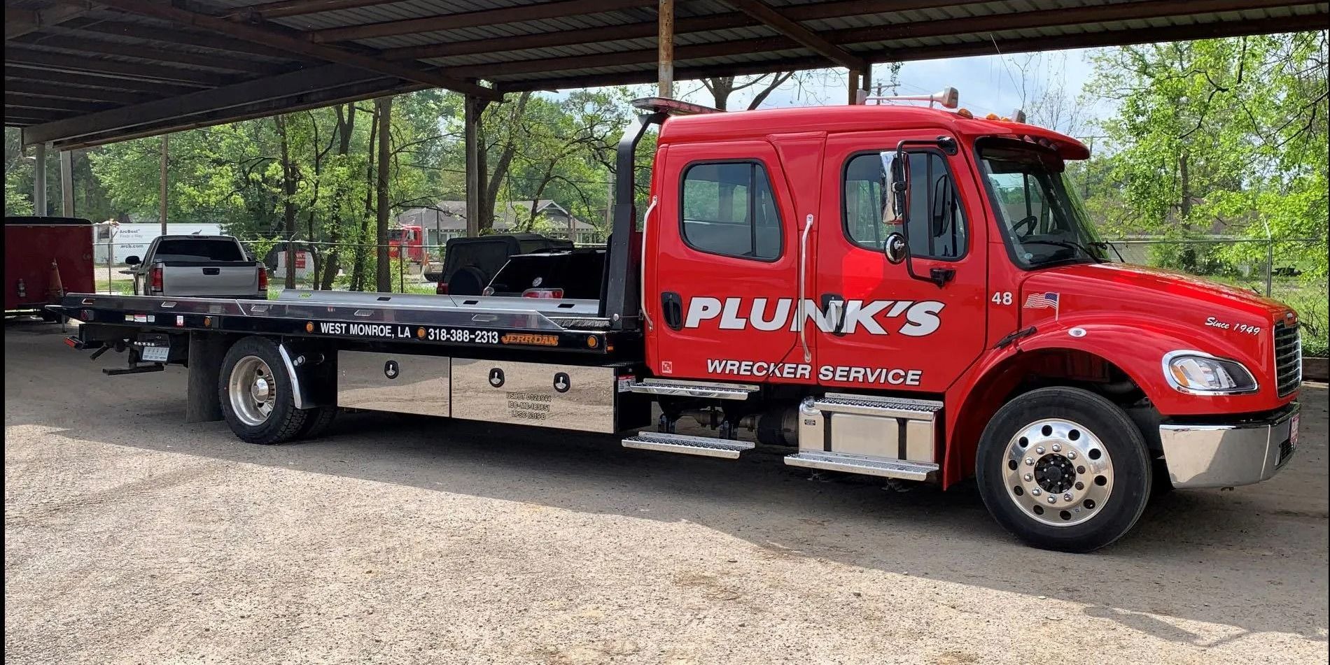 Red Punks towing truck with a black flatbed under a covered lot.