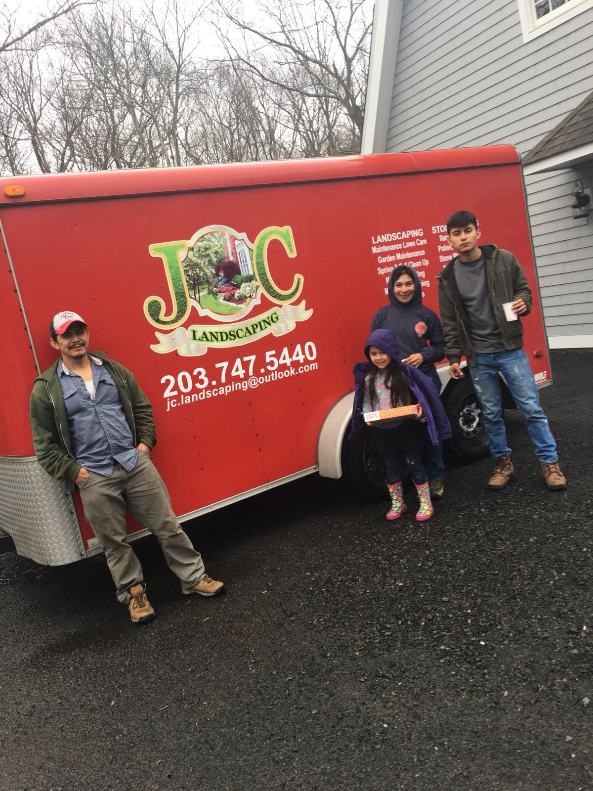 Group of people by a red JOC Landscaping trailer.