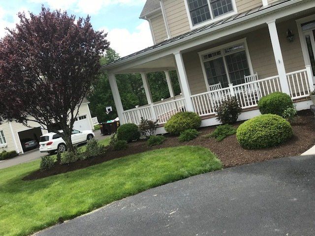 A well-landscaped house with a porch, lawn, and a tree.