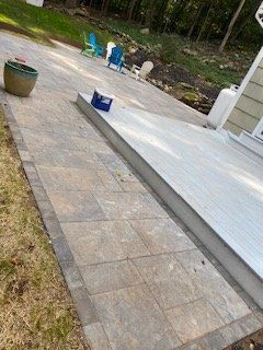 Stone patio with a concrete slab, chairs, and a propane tank.