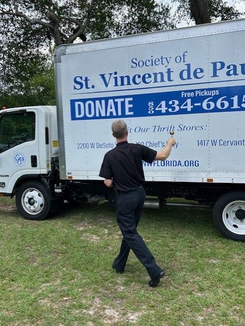 A man is standing in front of a donation truck from the society of st. vincent de paul