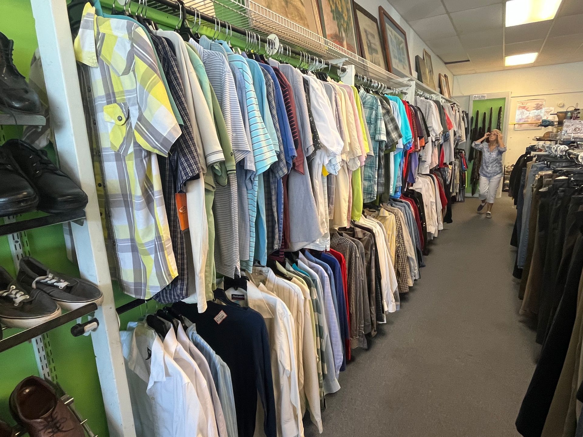 A woman is walking through a clothing store filled with clothes and shoes