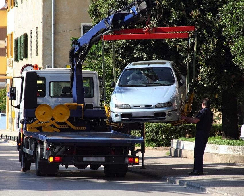 A white car is being lifted by a tow truck