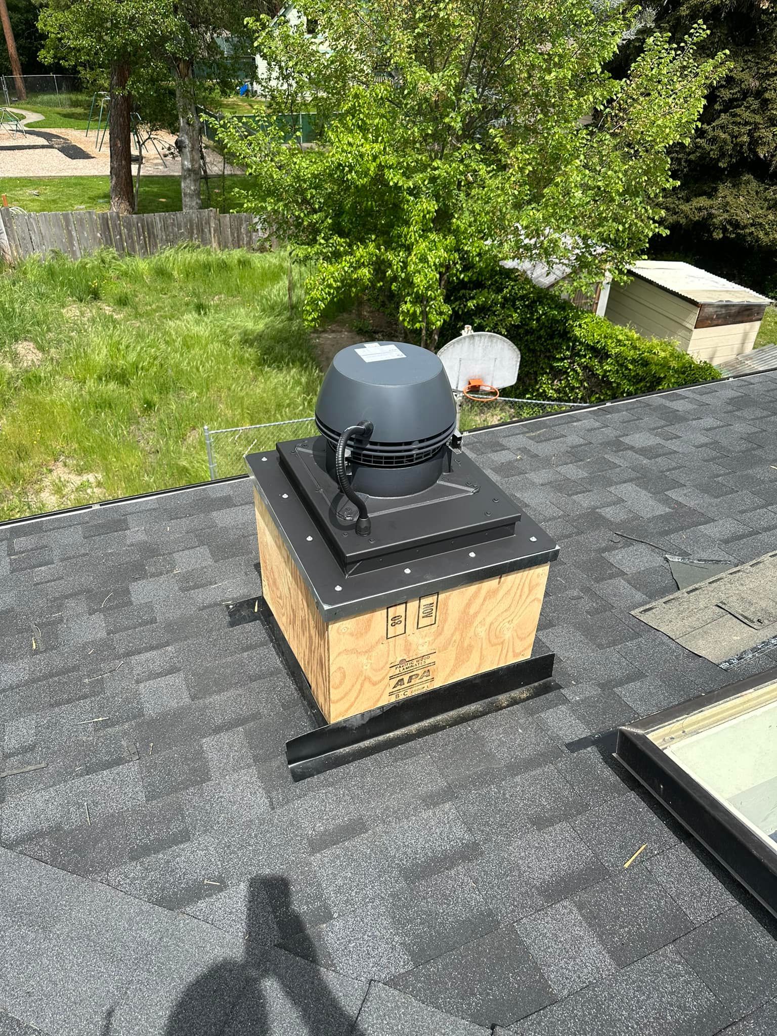 A roof with a chimney and a fan on it.