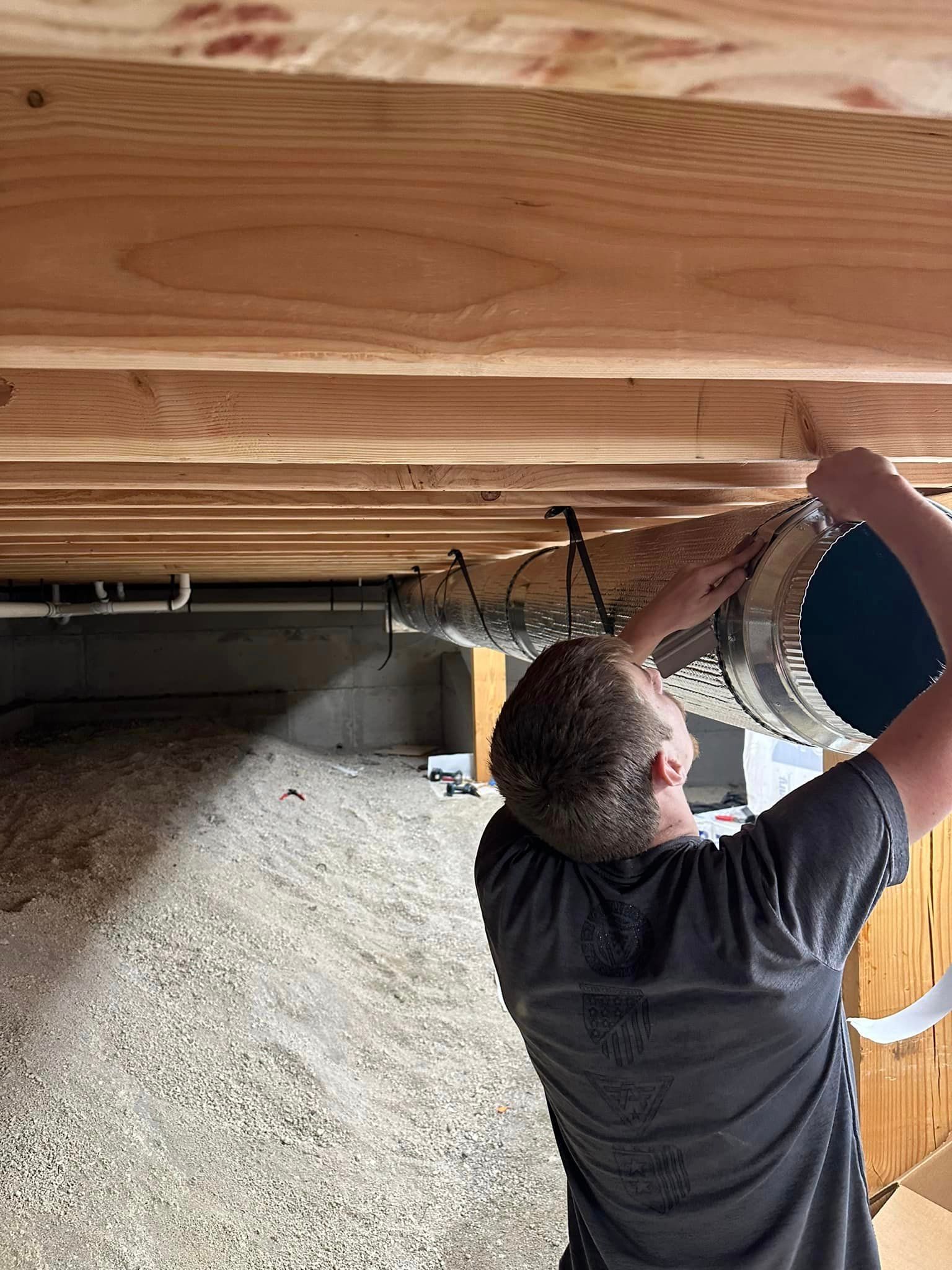 A man is working on a wooden ceiling in a basement.