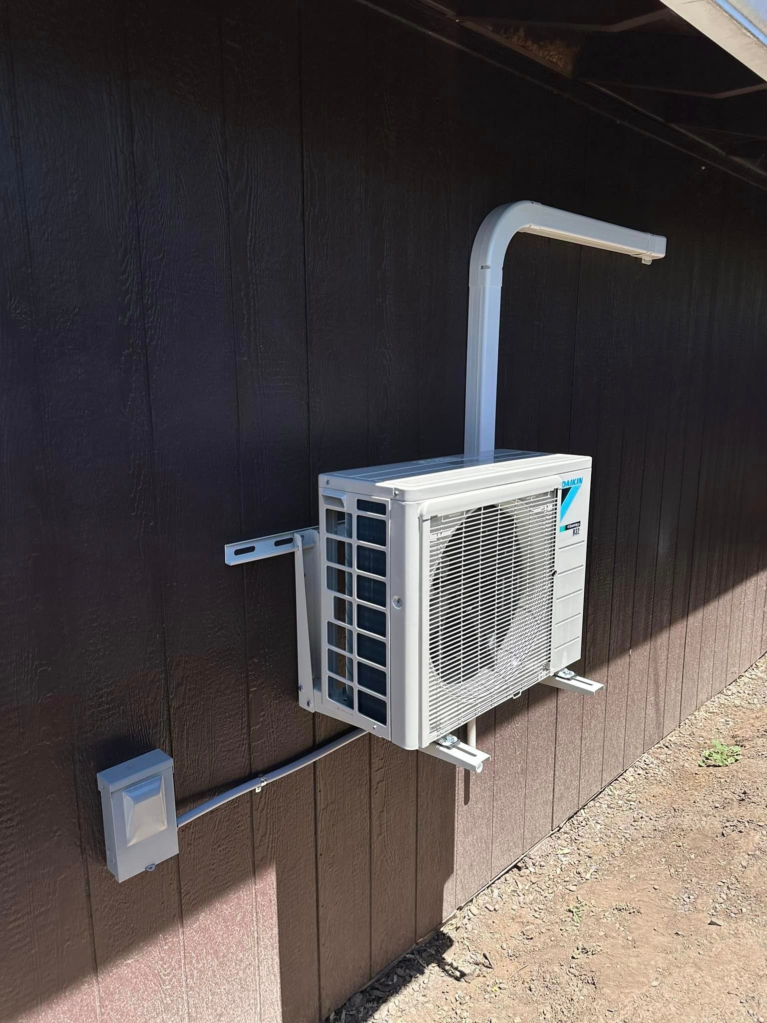 A white air conditioner is mounted to the side of a building.