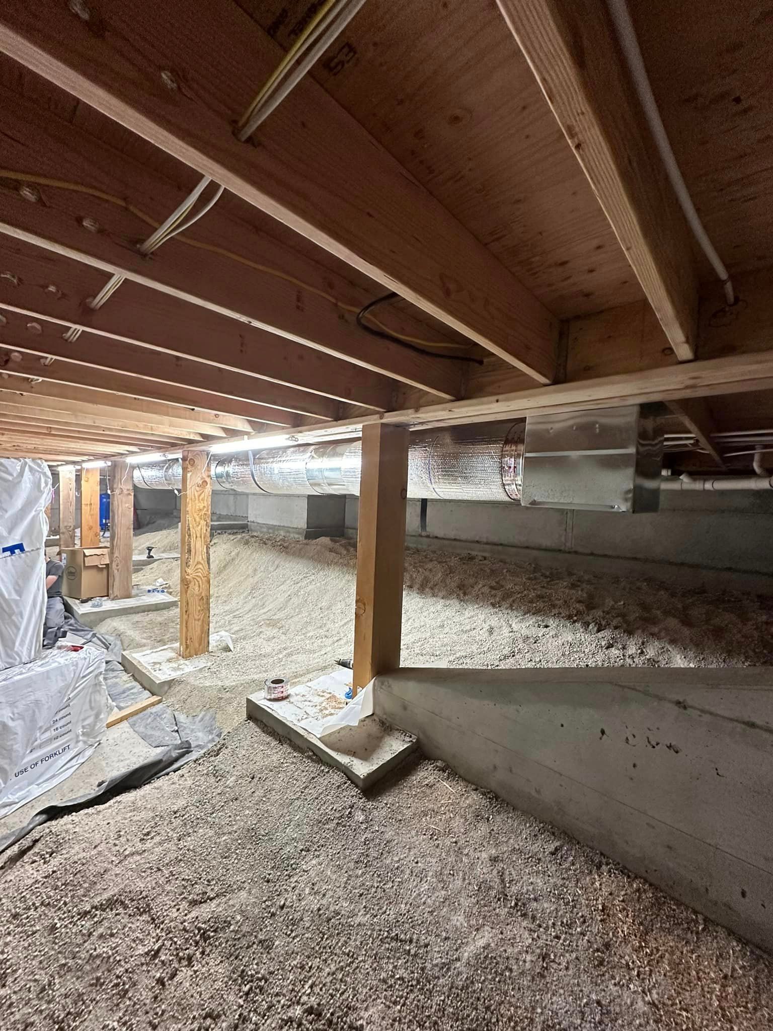 A basement under a house with wooden beams and insulation.