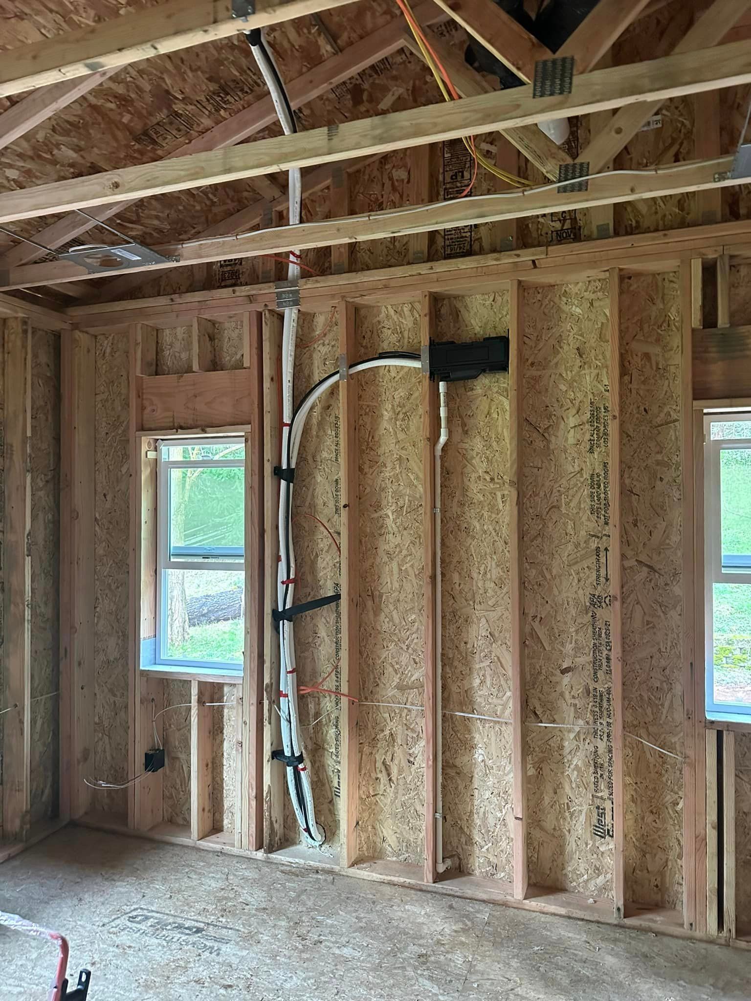 A room in a house under construction with a lot of wires hanging from the ceiling.