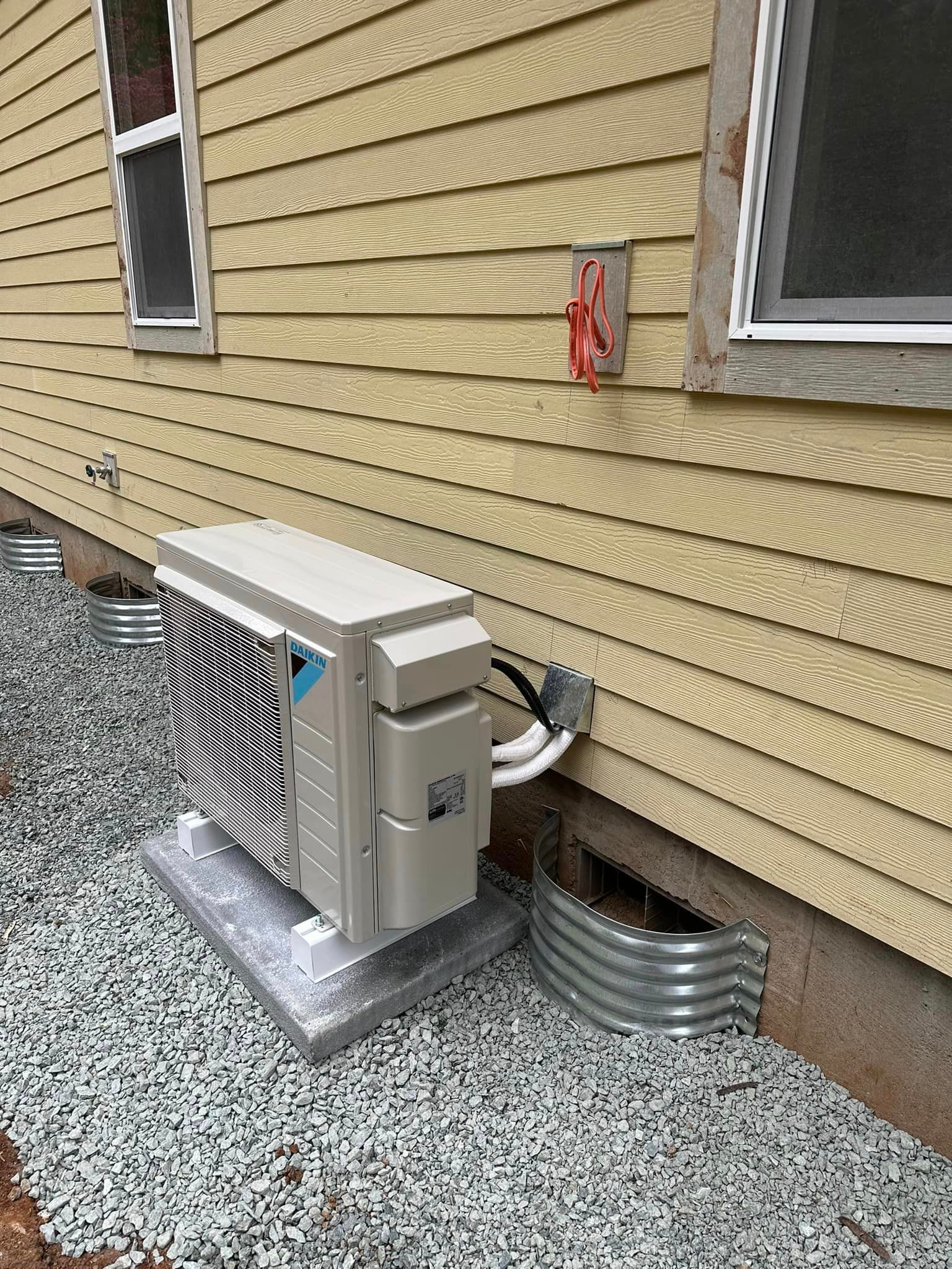 An air conditioner is sitting on the side of a house.