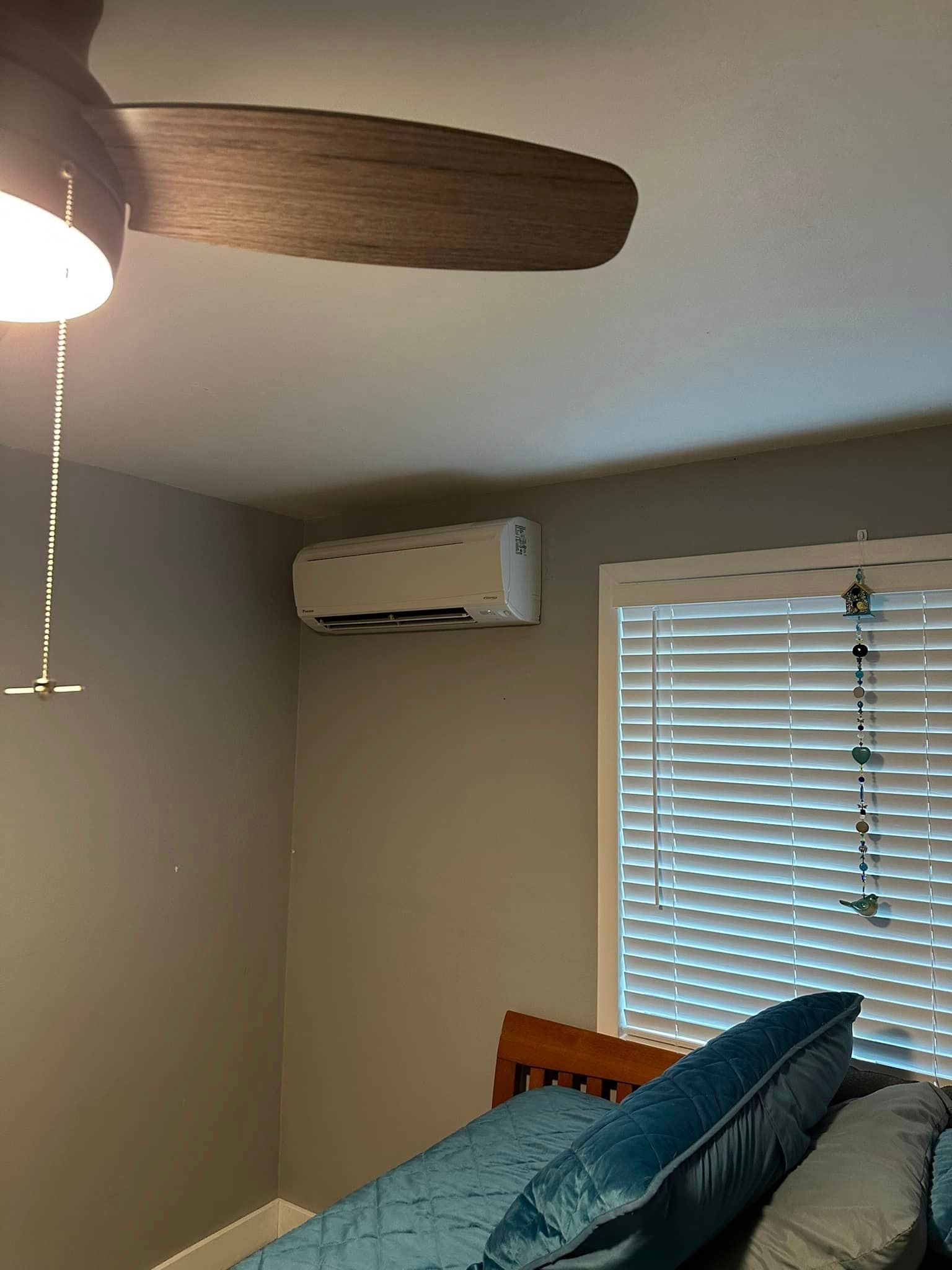A bedroom with a ceiling fan and a window with blinds.